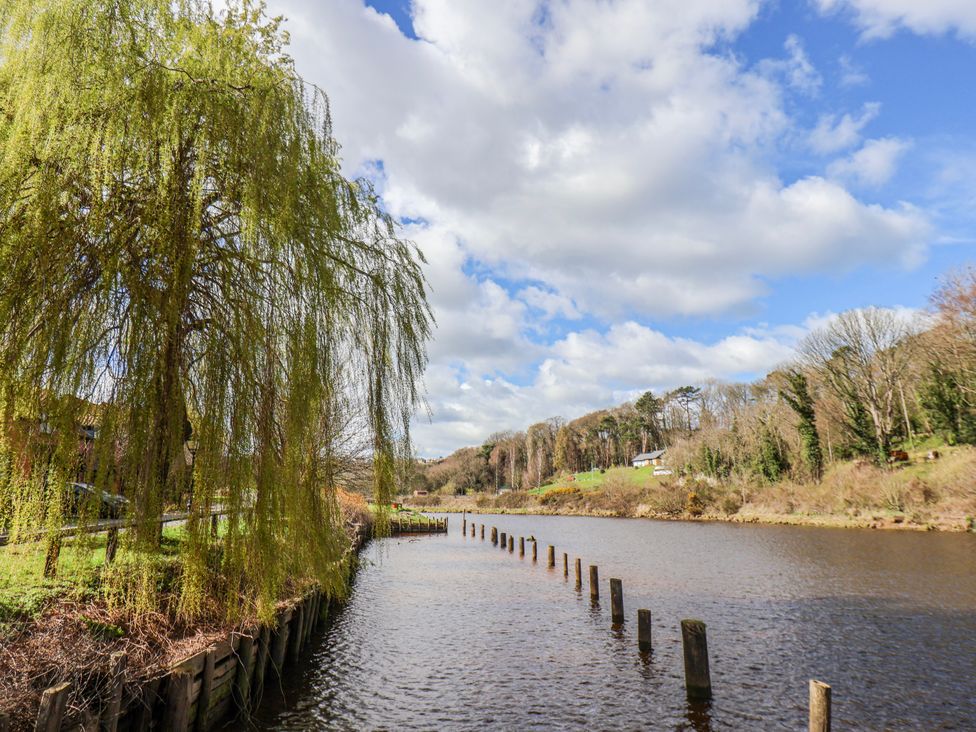 A river with wooden posts and a willow tree at Waterside Cottage in Whitby