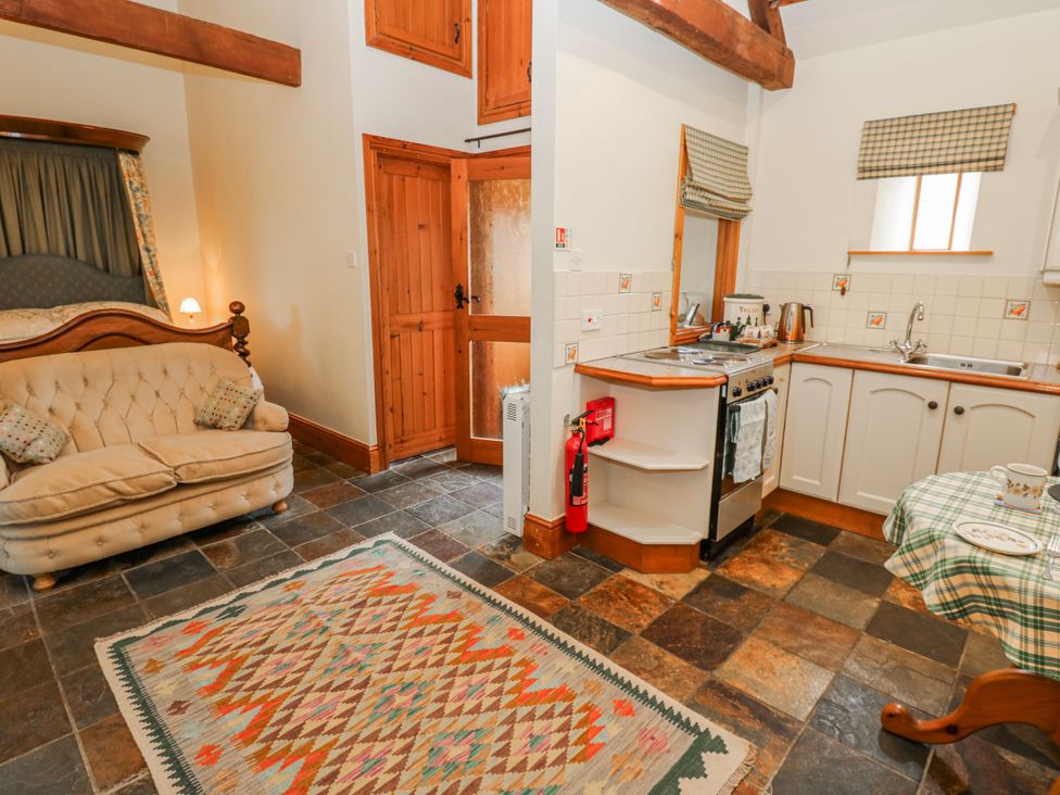 A living room with a sofa and kitchen area at Lovesome Cottage in Northallerton