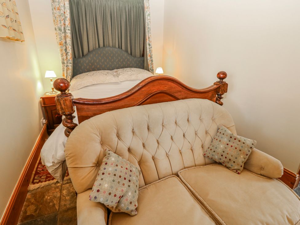 A bedroom with a bed and sofa at Lovesome Cottage in Northallerton