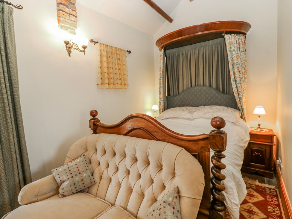 A bedroom with a bed and a sofa at Lovesome Cottage in Northallerton