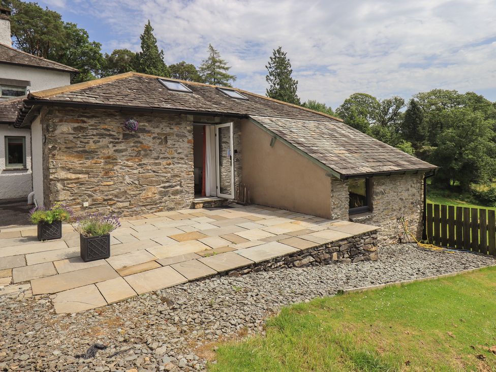 An outdoor area with a stone wall and patio at Acorn in Bowness-on-Windermere