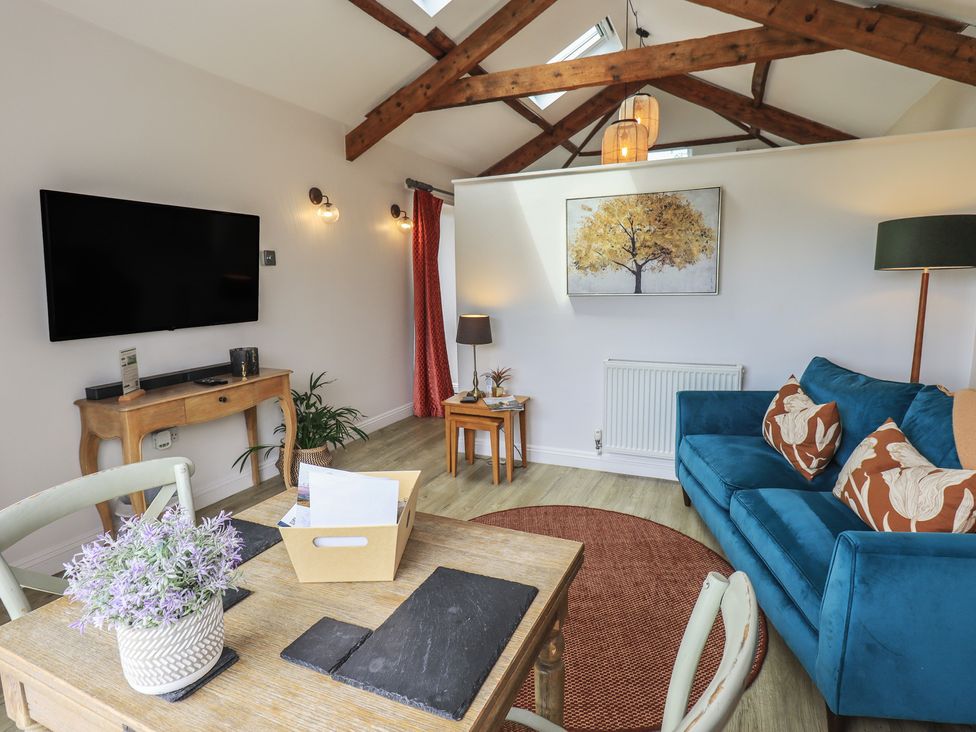 A living room with a television and sofa at Acorn in Bowness-on-Windermere