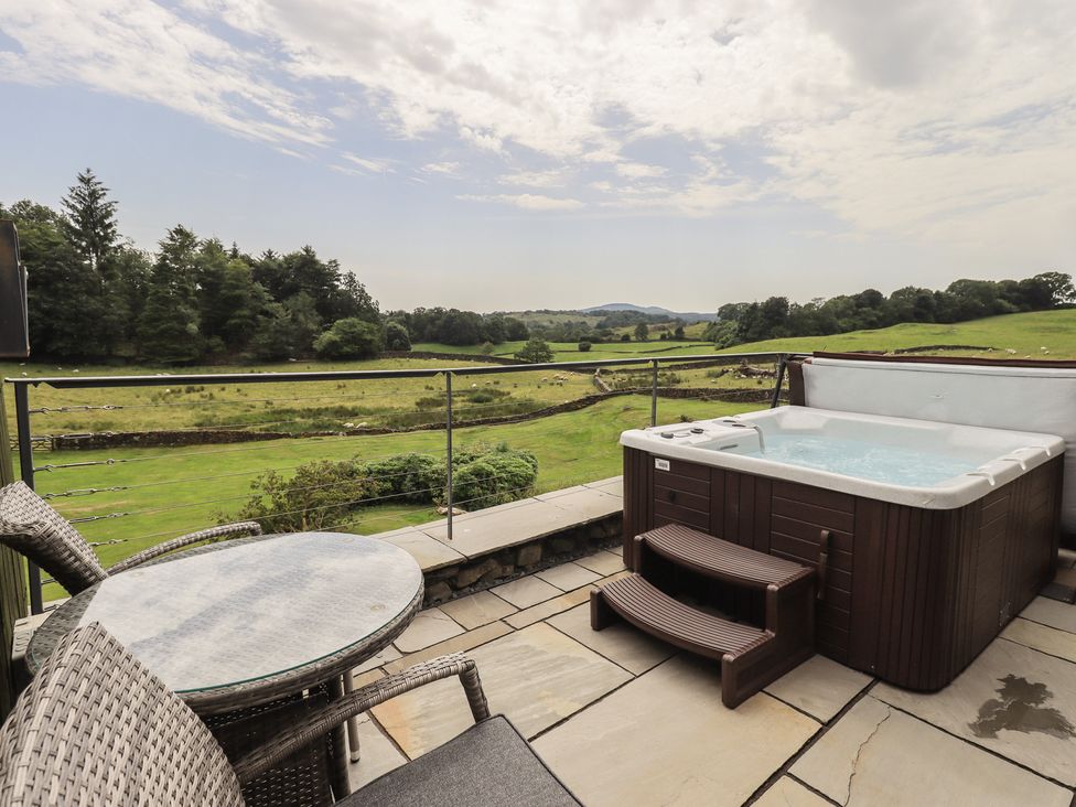 An outdoor area with a hot tub and seating at Acorn in Bowness-on-Windermere