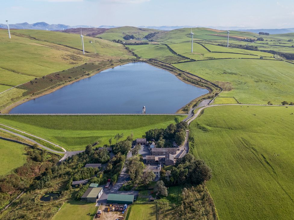 An aerial view of a lake and fields with wind turbines near Ash Lodge Pennington near Ulverston