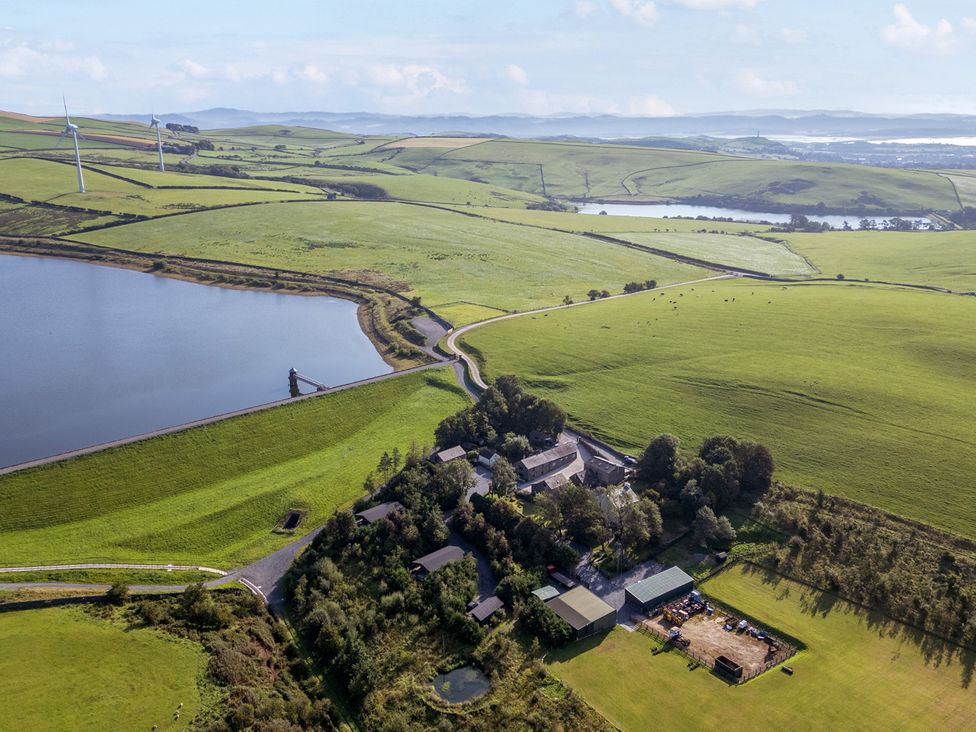 An aerial view of fields and buildings near a water body at Ash Lodge in Pennington near Ulverston