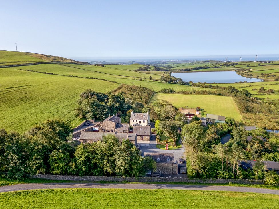 An aerial view of a property surrounded by fields and a lake at Ash Lodge in Pennington near Ulverston