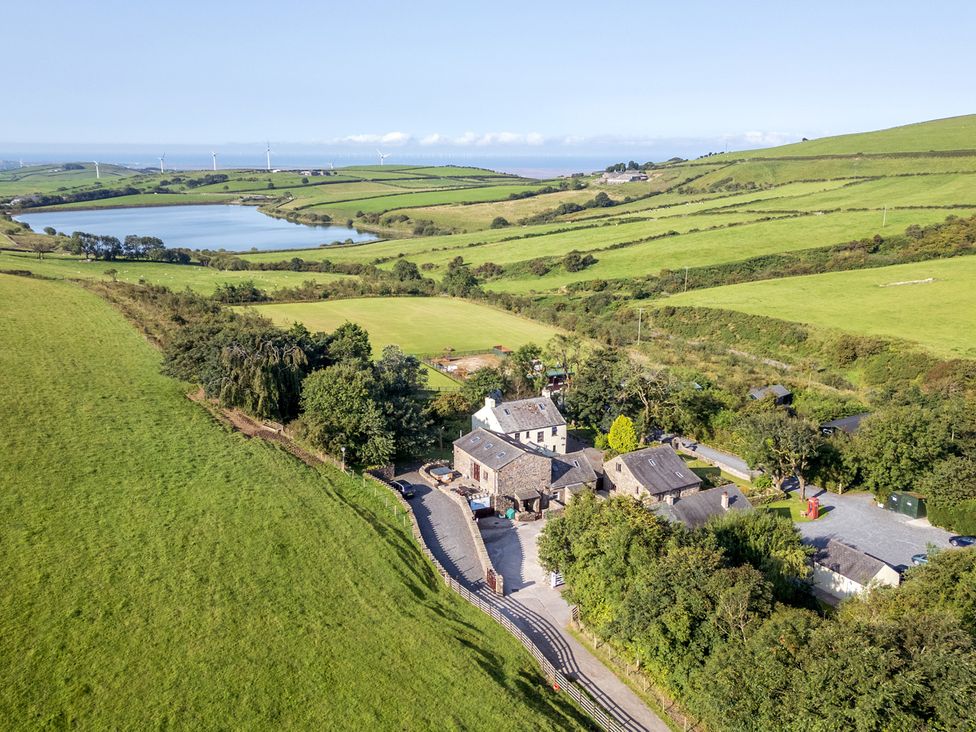 An aerial view of a house near a lake and fields at Ash Lodge Pennington near Ulverston
