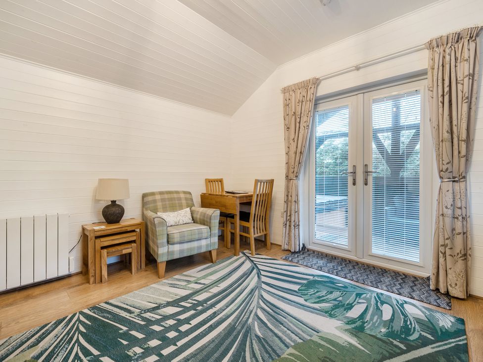 A living room with an armchair and dining table at Ash Lodge Pennington near Ulverston