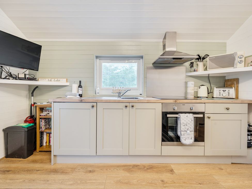 A kitchen with cabinets, sink, oven and television at Ash Lodge in Pennington near Ulverston