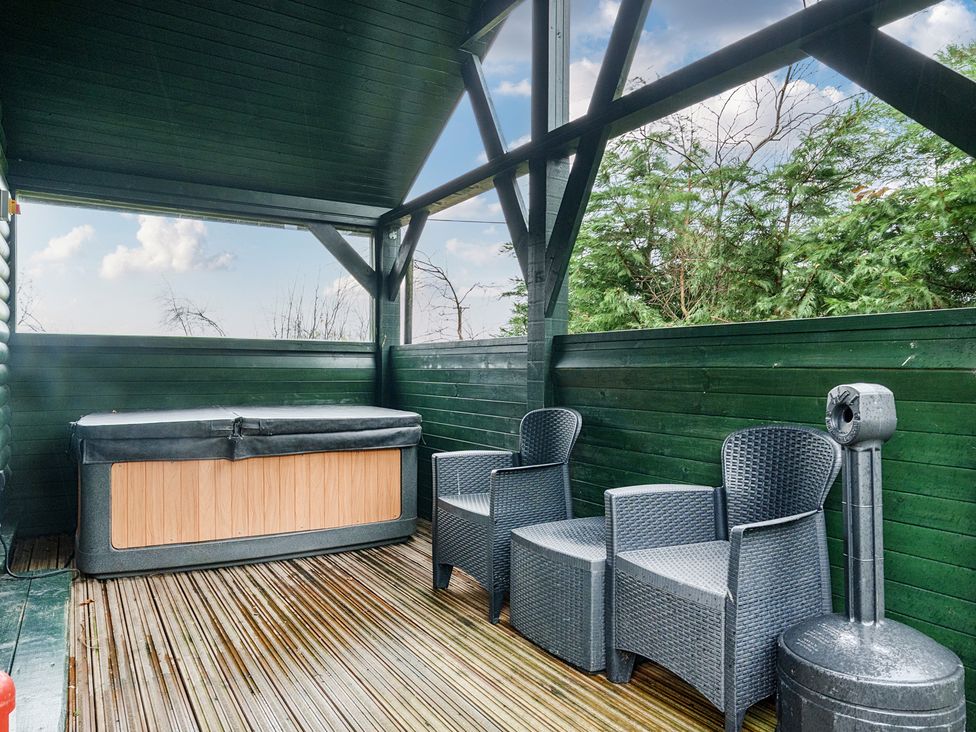 An outdoor area with a hot tub and chairs at Ash Lodge in Pennington near Ulverston