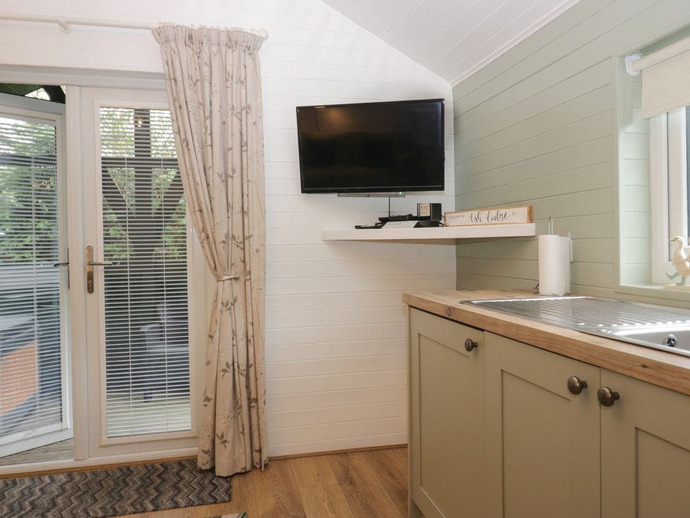 A kitchen with a window and television at Ash Lodge Pennington near Ulverston