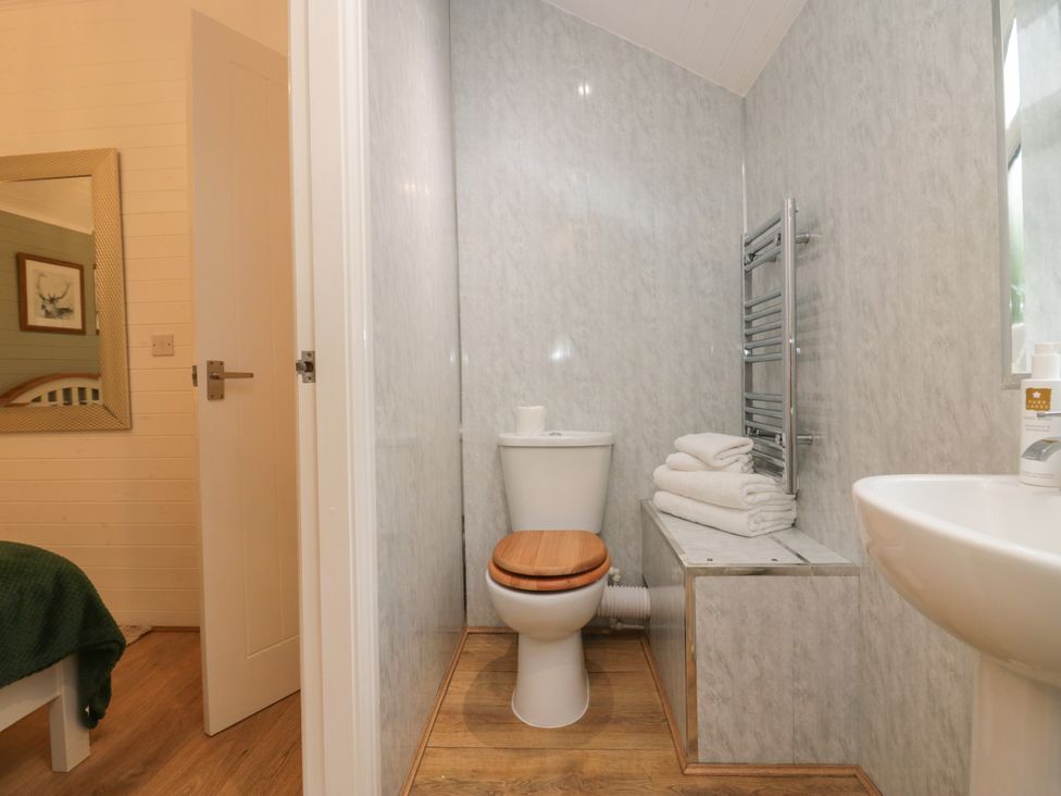 A bathroom with a toilet, sink, towels and a mirror at Ash Lodge, Pennington near Ulverston