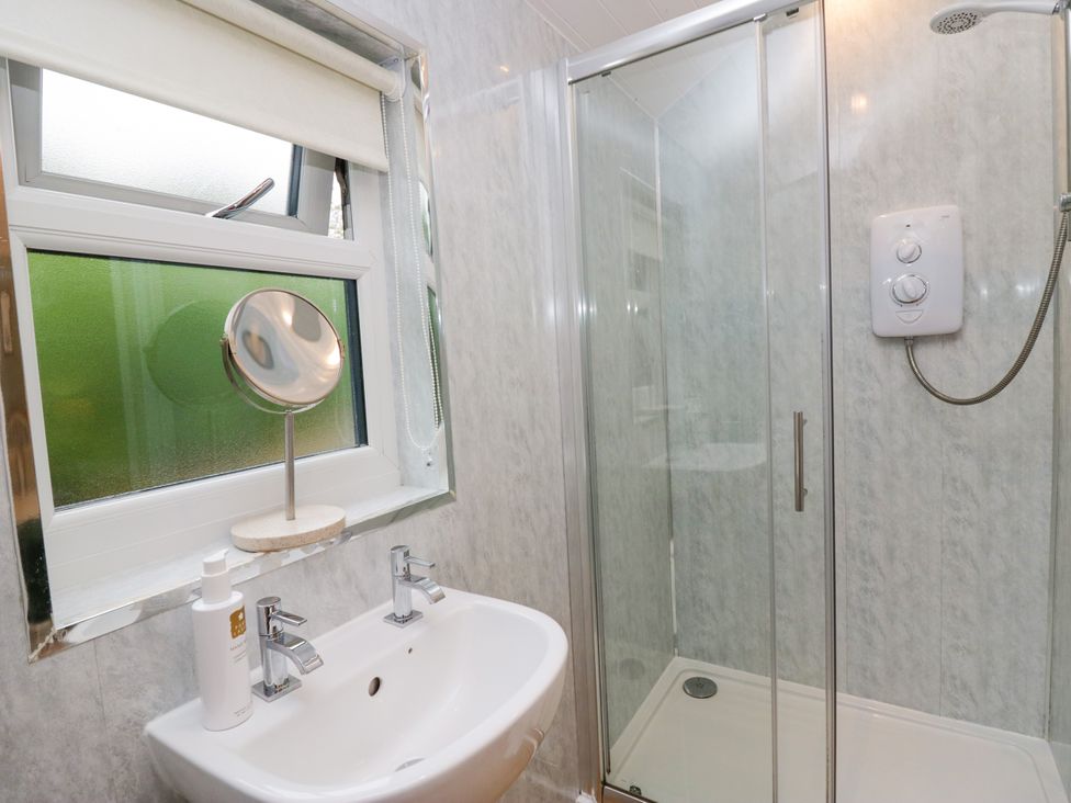 A bathroom with a sink, mirror, and shower at Ash Lodge in Pennington near Ulverston