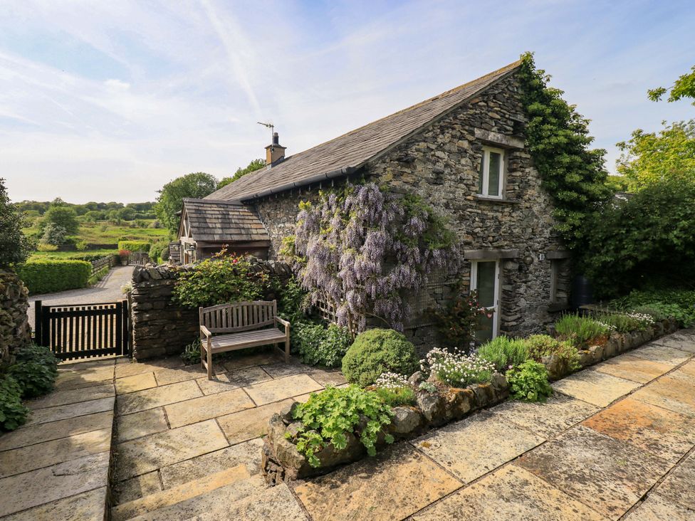A stone cottage with a bench and garden at Pheasant Cottage in Beckside near Cartmel