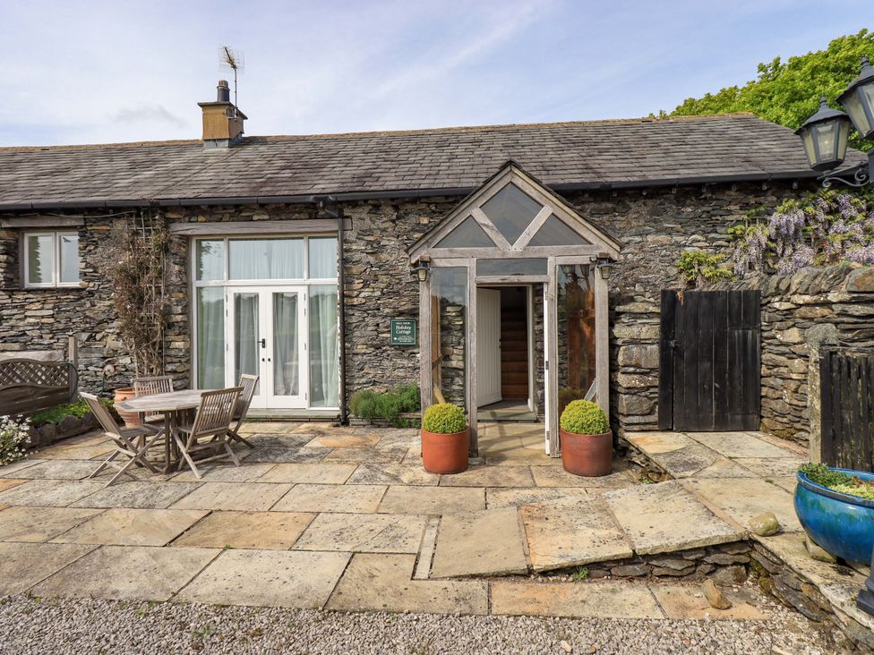 An entrance with stone walls and outdoor seating at Pheasant Cottage in Beckside near Cartmel