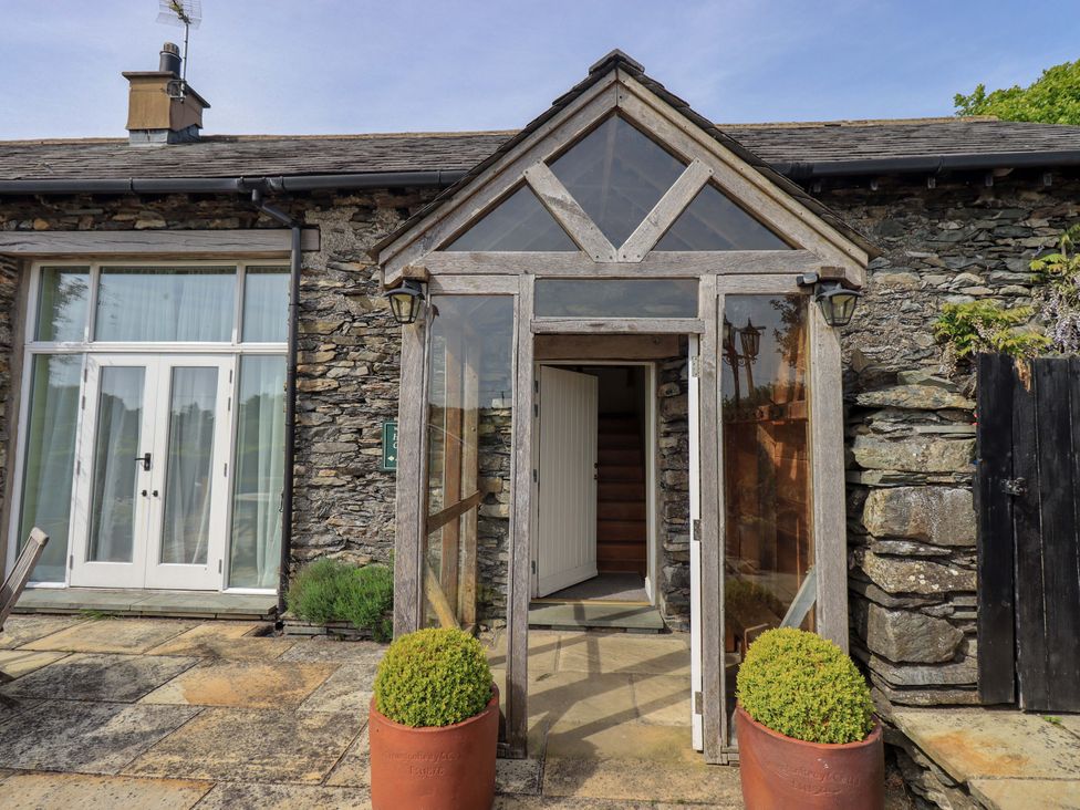 A glass entrance with stone walls and planters at Pheasant Cottage in Beckside near Cartmel