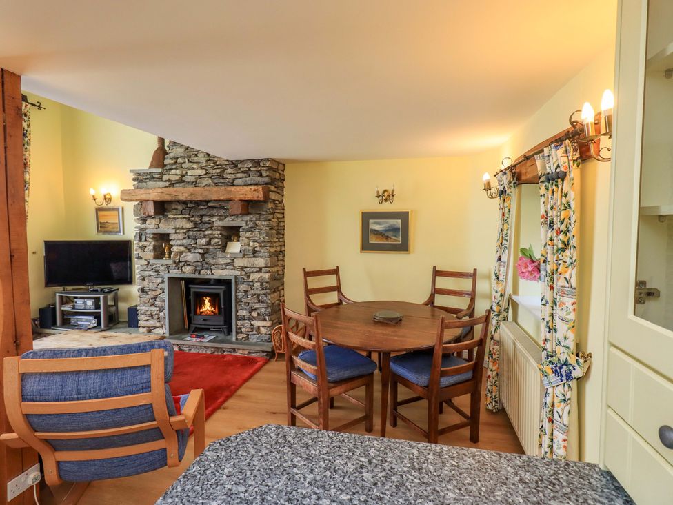 A living room with a fireplace and dining table at Pheasant Cottage Beckside near Cartmel