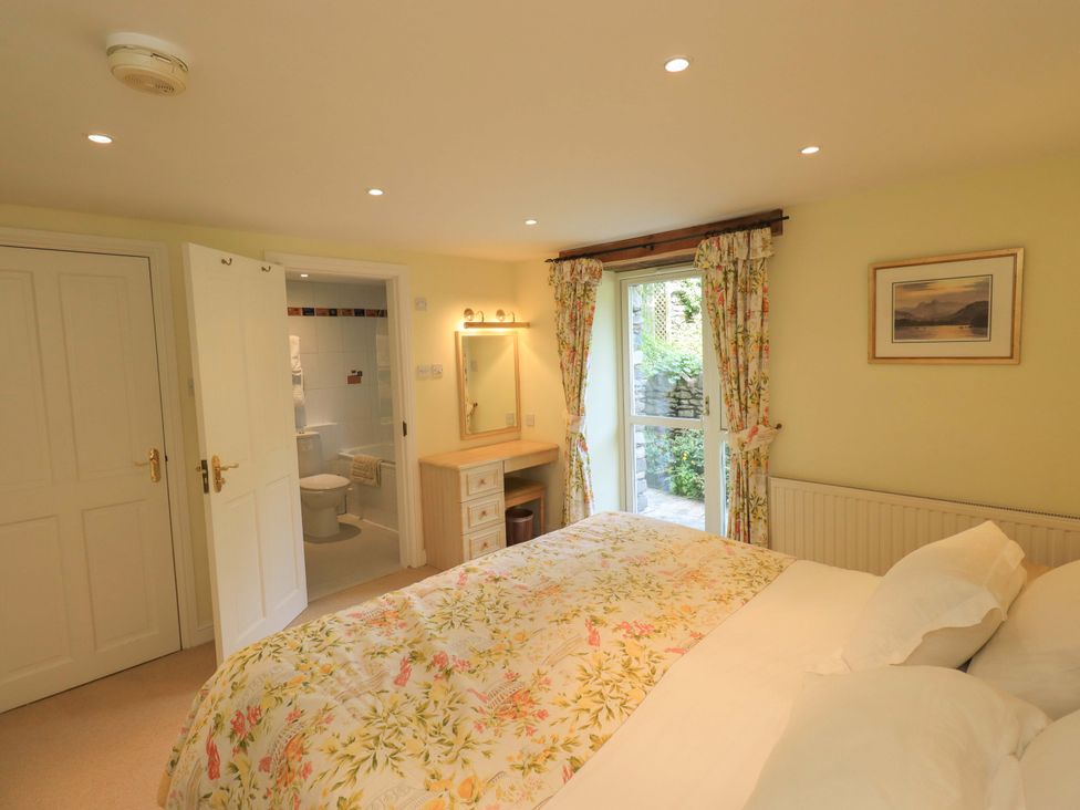 A bedroom with a bed and dressing table at Pheasant Cottage Beckside near Cartmel