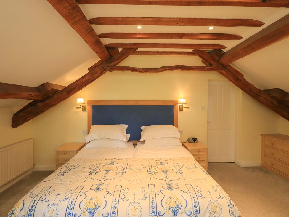 A bedroom with a bed and bedside table at Pheasant Cottage Beckside near Cartmel