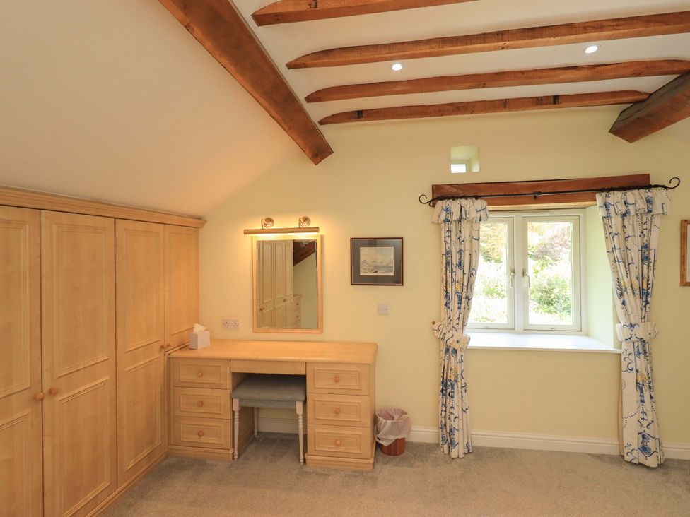 A bedroom with a wardrobe and a dresser at Pheasant Cottage Beckside near Cartmel