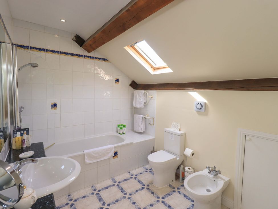 A bathroom with a bathtub, toilet, sink, and bidet at Pheasant Cottage in Beckside near Cartmel