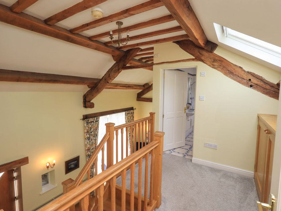 A hallway with staircase and wood beams at Pheasant Cottage in Beckside near Cartmel