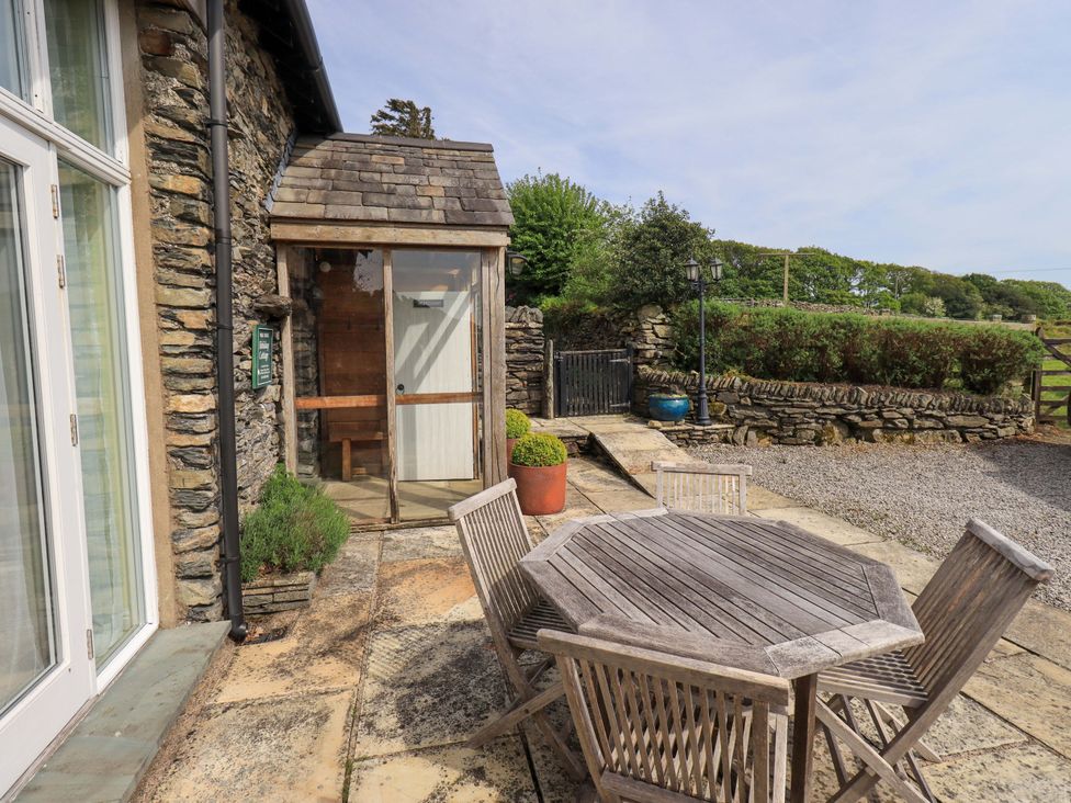 An outdoor seating area with a wooden table and chairs at Pheasant Cottage Beckside near Cartmel