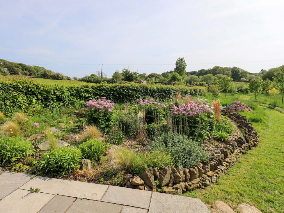 A garden with flowers and grass at Pheasant Cottage Beckside near Cartmel