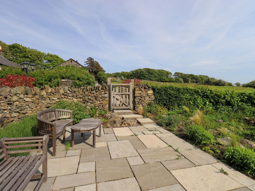 A garden with a stone pathway and a wooden gate at Pheasant Cottage Beckside near Cartmel