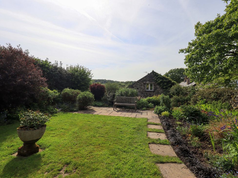 A garden with a bench and plants at Pheasant Cottage in Beckside near Cartmel