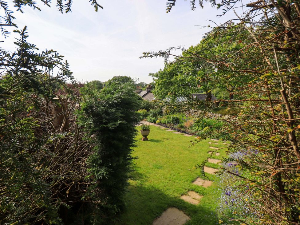 A garden with grass and a pathway at Pheasant Cottage Beckside near Cartmel