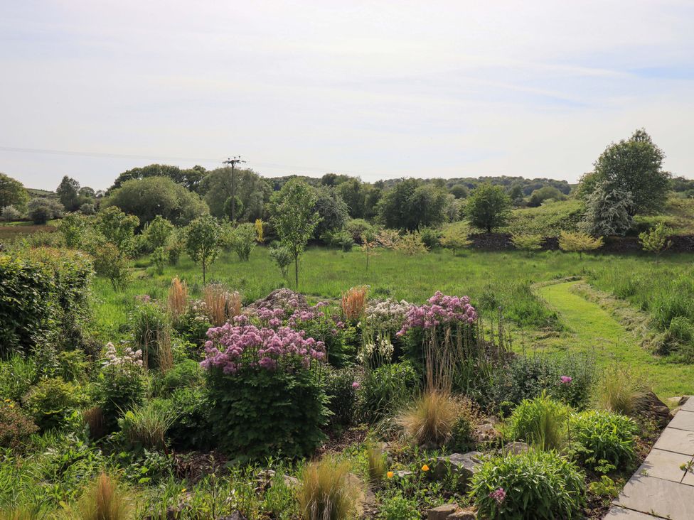A garden with flowers and greenery at Pheasant Cottage Beckside near Cartmel