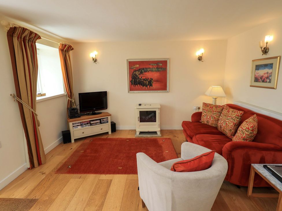 A living room with a sofa and television at Kestrel Cottage near Cartmel