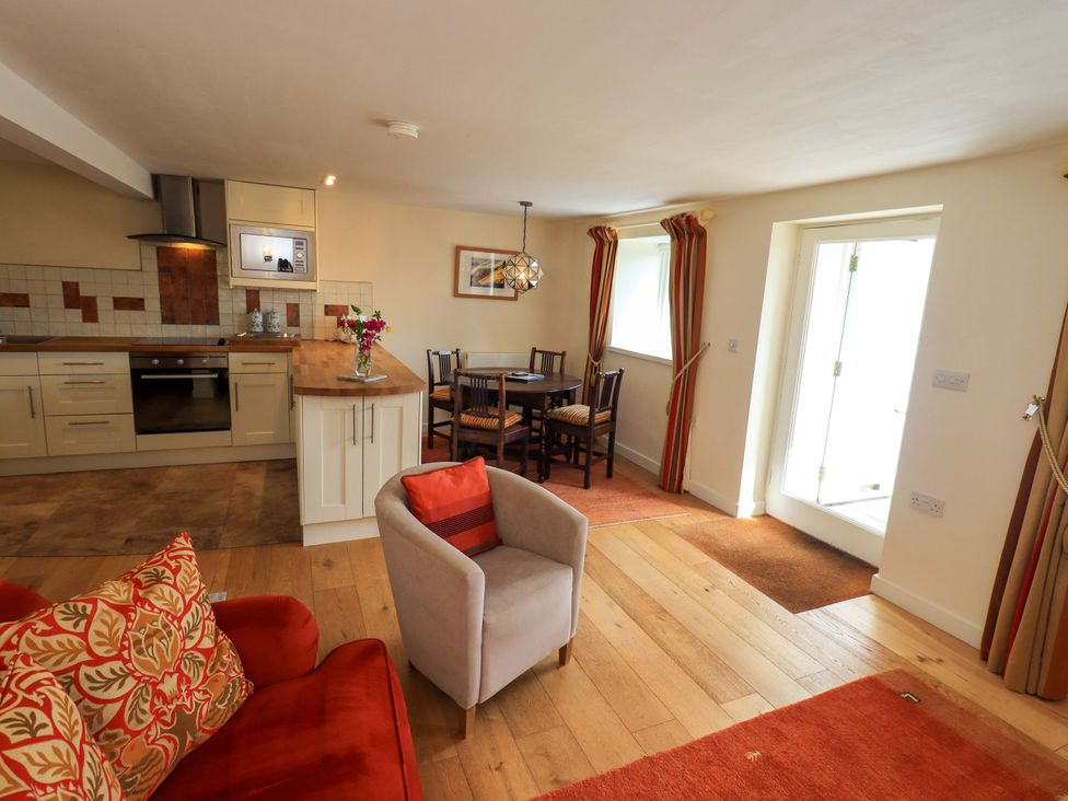 A dining area with kitchen and seating at Kestrel Cottage Beckside near Cartmel