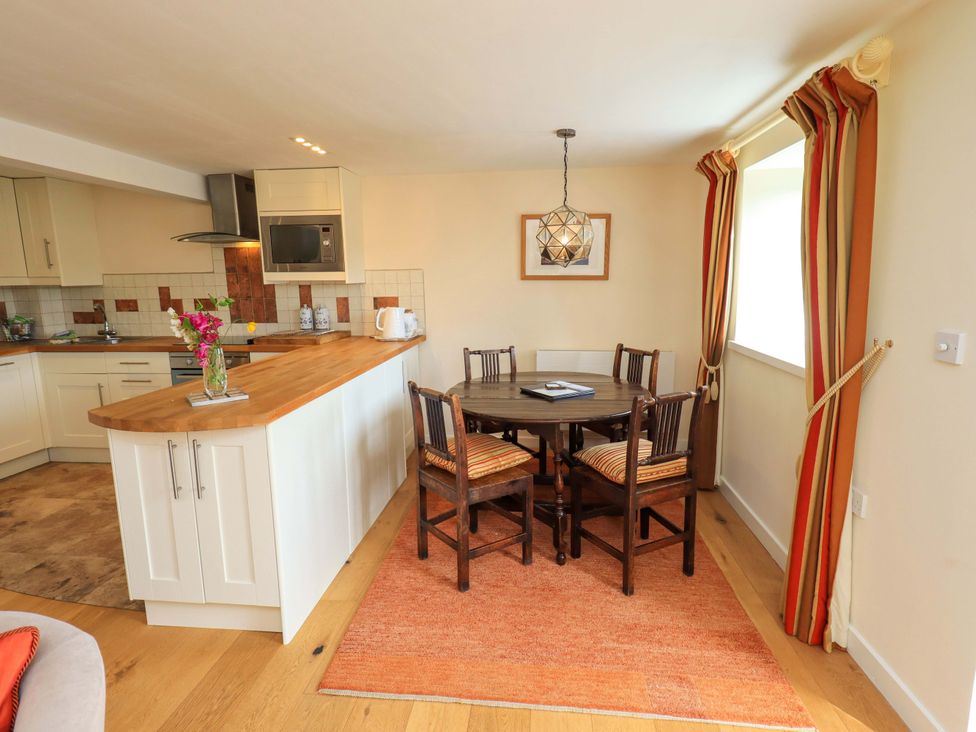 A kitchen with a dining area featuring a table and chairs at Kestrel Cottage Beckside near Cartmel