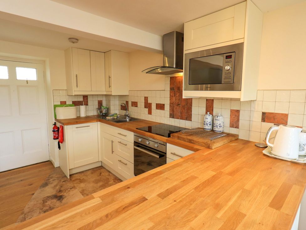 A kitchen with cabinets and appliances at Kestrel Cottage in Beckside near Cartmel
