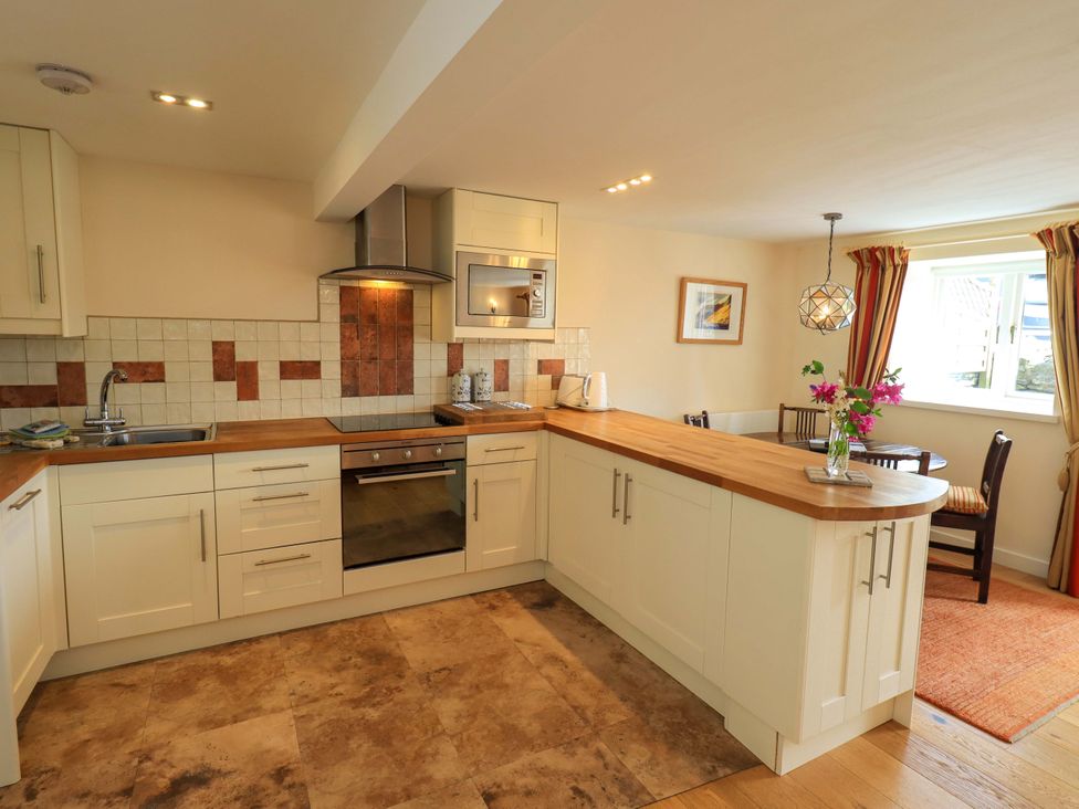 A kitchen with cabinets and a countertop at Kestrel Cottage Beckside near Cartmel