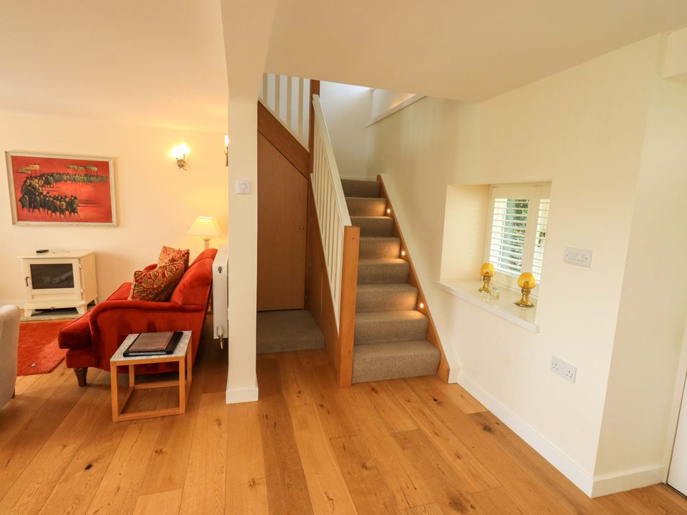 A living room with a staircase and sofa at Kestrel Cottage Beckside near Cartmel