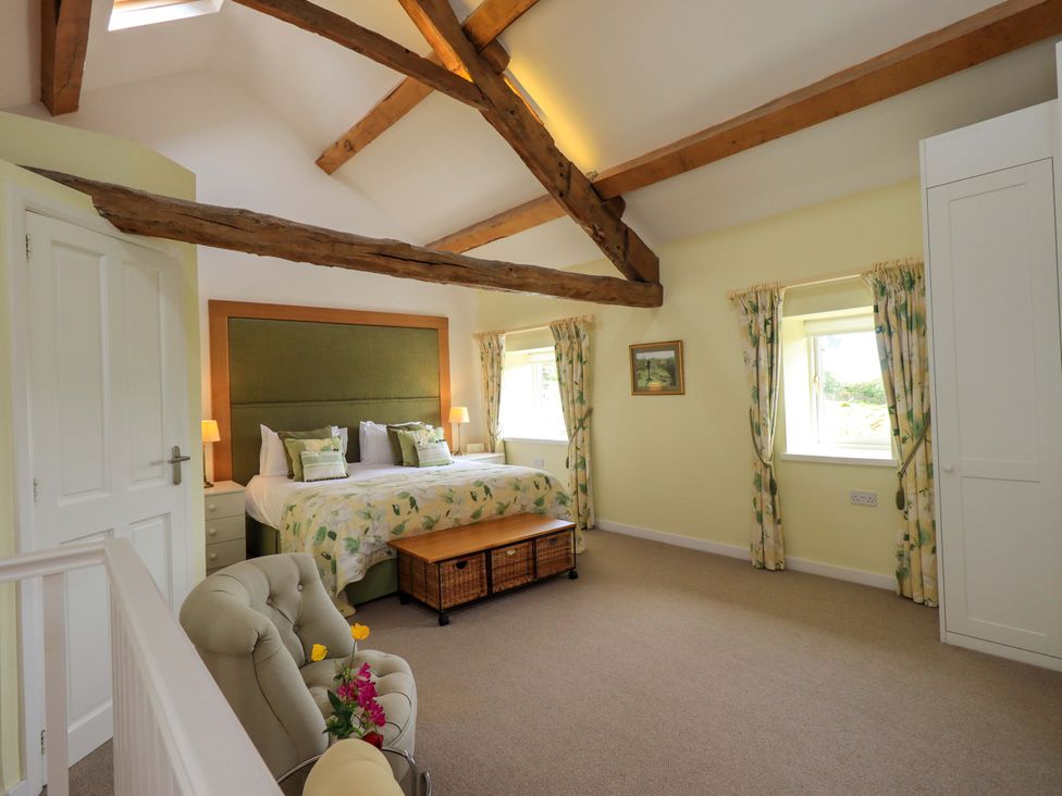 A bedroom with a bed and windows at Kestrel Cottage in Beckside near Cartmel