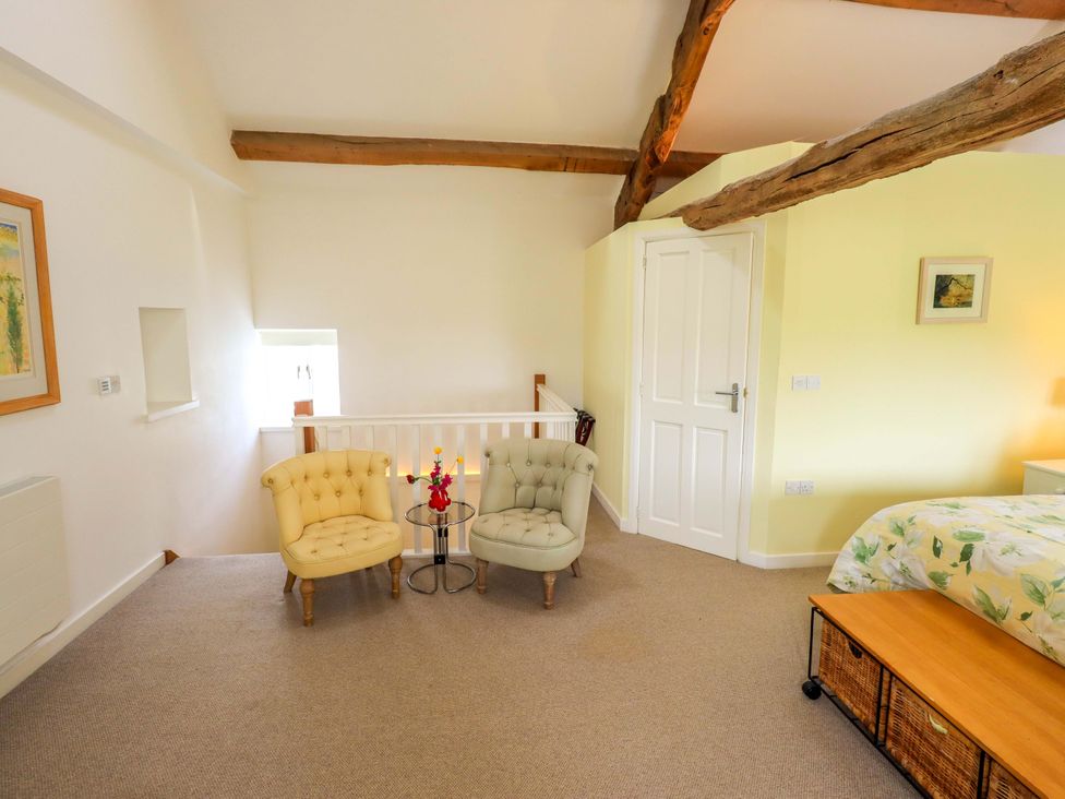 A bedroom with two armchairs and a side table at Kestrel Cottage Beckside near Cartmel