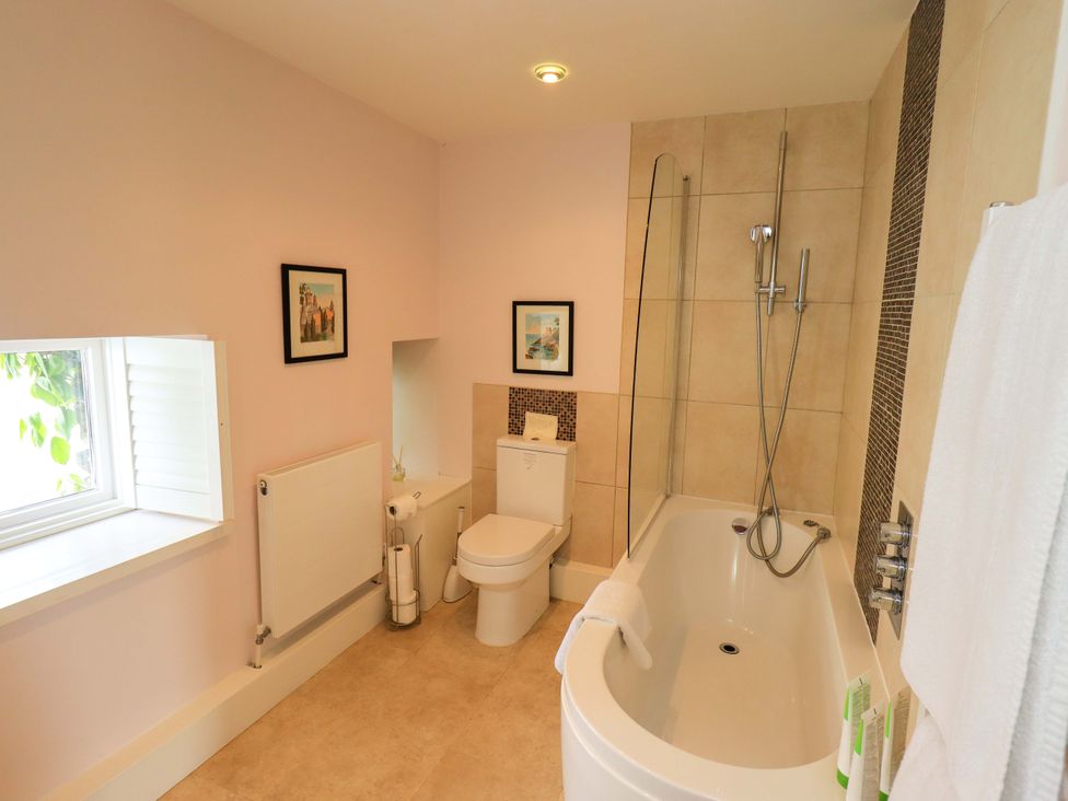 A bathroom with a bathtub, toilet, and radiator at Kestrel Cottage, Beckside near Cartmel