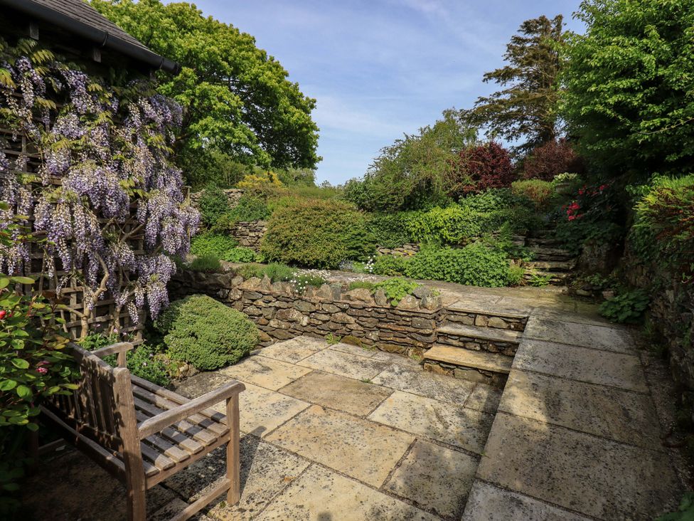 A garden with a stone pathway and plants at Kestrel Cottage in Beckside near Cartmel