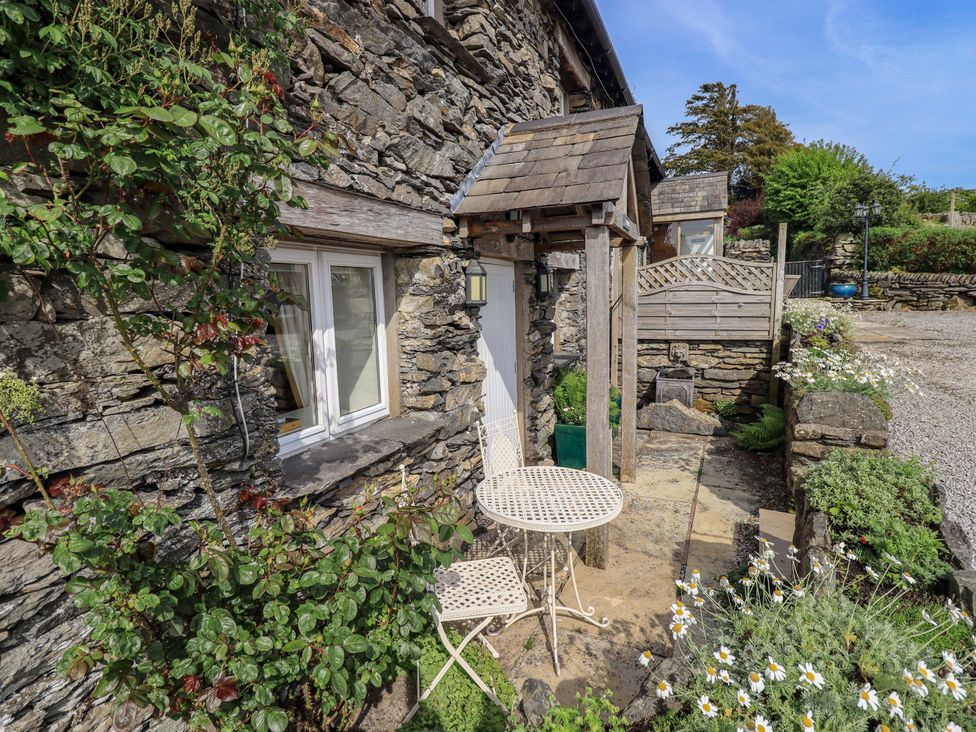 An outdoor area with a table and chair at Kestrel Cottage Beckside near Cartmel