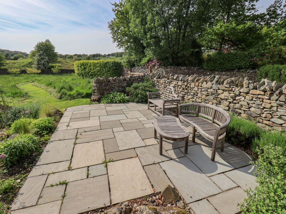 An outdoor area with a stone patio and seating at Kestrel Cottage Beckside near Cartmel