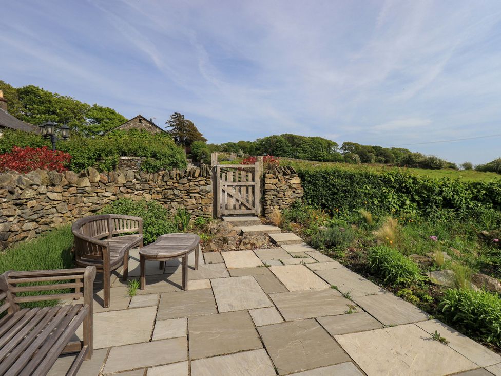 A garden with seating area and stone wall at Kestrel Cottage Beckside near Cartmel