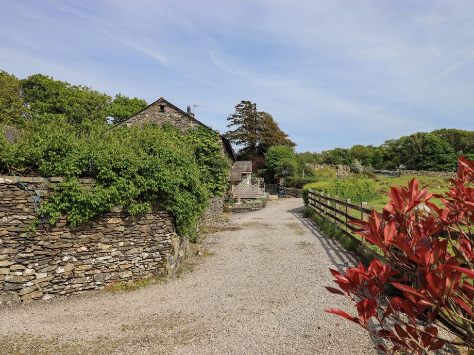 A gravel path leading to a building surrounded by greenery at Kestrel Cottage Beckside near Cartmel