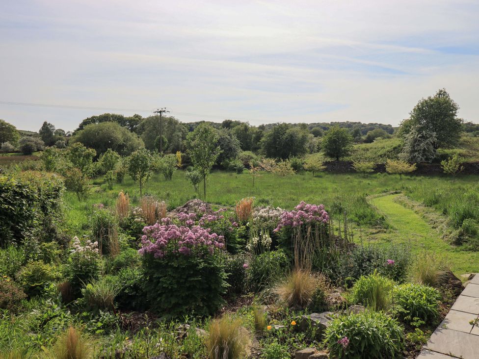 A garden view with flowers and a pathway at Kestrel Cottage near Cartmel