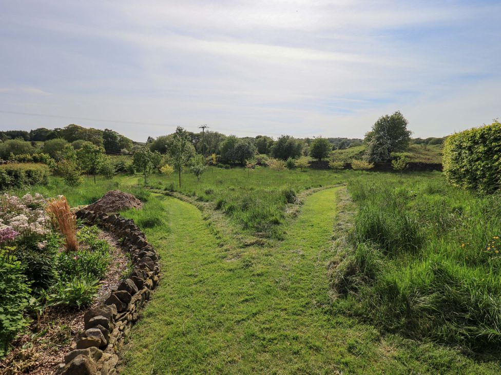 A garden with paths and trees at Kestrel Cottage in Beckside near Cartmel