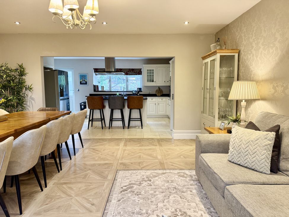 A dining room with a table and chairs leading to a kitchen at Willow Brook in Glossop