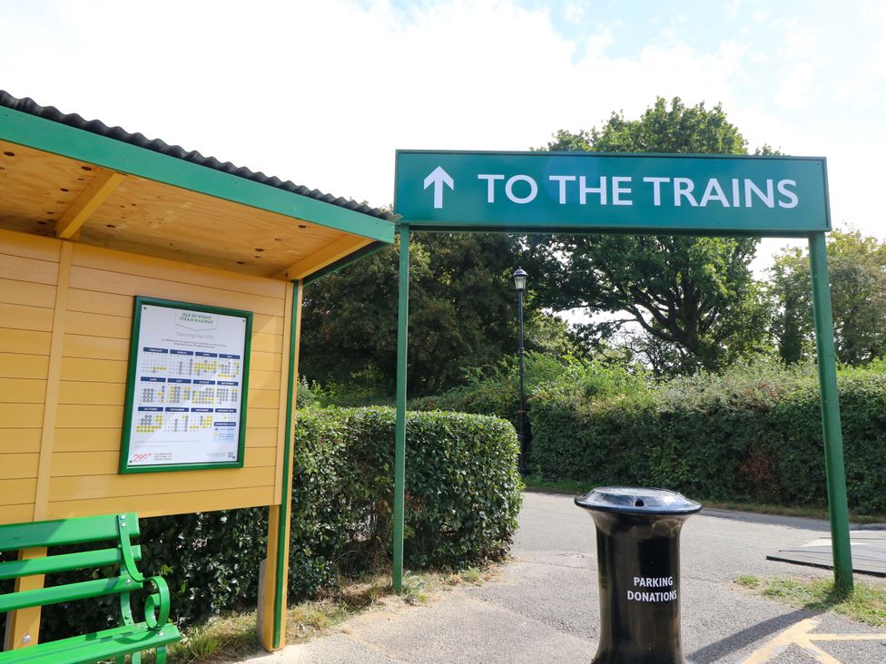 A sign pointing to the trains with a schedule board and bench at The Coach House Wootton Bridge
